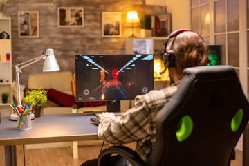 Back view of gamer male playing a shooter on his powerful PC computer late at night in the living room © DC Studio