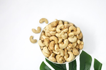 Cashews are in a cup with decorative leaves on the side.
