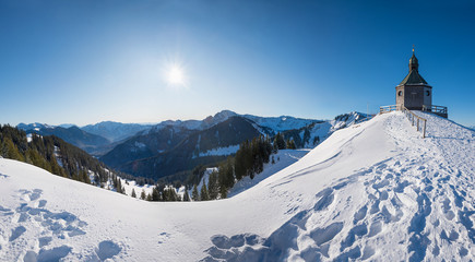beautiful chapel in winter landscape, popular tourist destination with view to bavarian alps