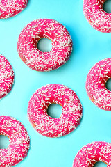 Donuts with icing on pastel pink background.