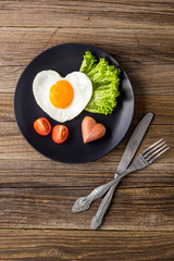 Valentines day breakfast with heart shaped fried eggs served on grey plate.