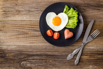 Valentines day breakfast with heart shaped fried eggs served on grey plate.