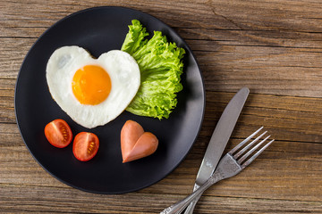 Valentines day breakfast with heart shaped fried eggs served on grey plate.