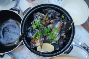 Mussels in a cauldron with cream sauce and herbs. Bar of mussels. Dinner with a beer. Dinner with vermouth.