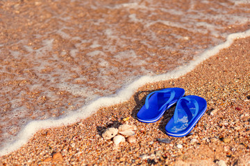 Fototapeta na wymiar Pair of flip flops on the beach and water flow.