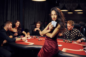 Portrait of beautiful woman. Group of elegant young people that playing poker in casino together