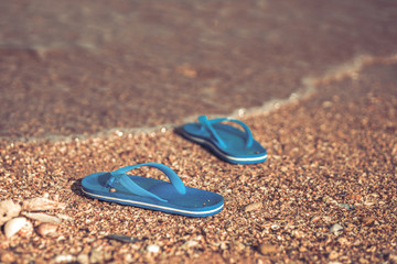 Pair of flip flops on the beach and water flow.
