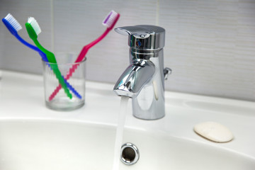 Water Tap, Toothbrushes, Soap and Running Water in a Sink