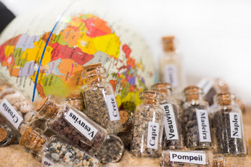 Glass test-tube with sand of different summer vacation countries. Located in sand with small globe.