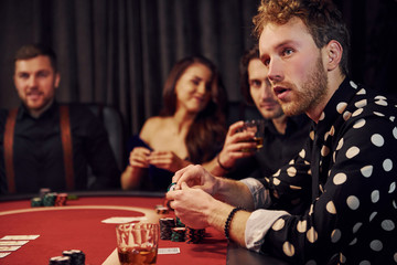 Side view of group of elegant young people that playing poker in casino together