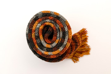 Rolled up colored hand knitting scarf on a white background.