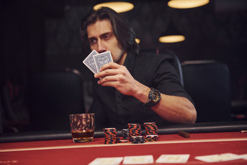 Elegant young man sits in casino and plays poker game