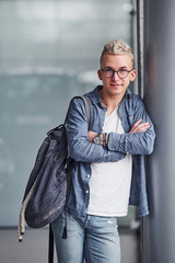 Obraz premium Young hipster guy in nice clothes stands indoors against grey background
