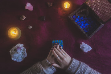 Young woman starting a tarot card reading with a mystical background of candles, stones and crystals