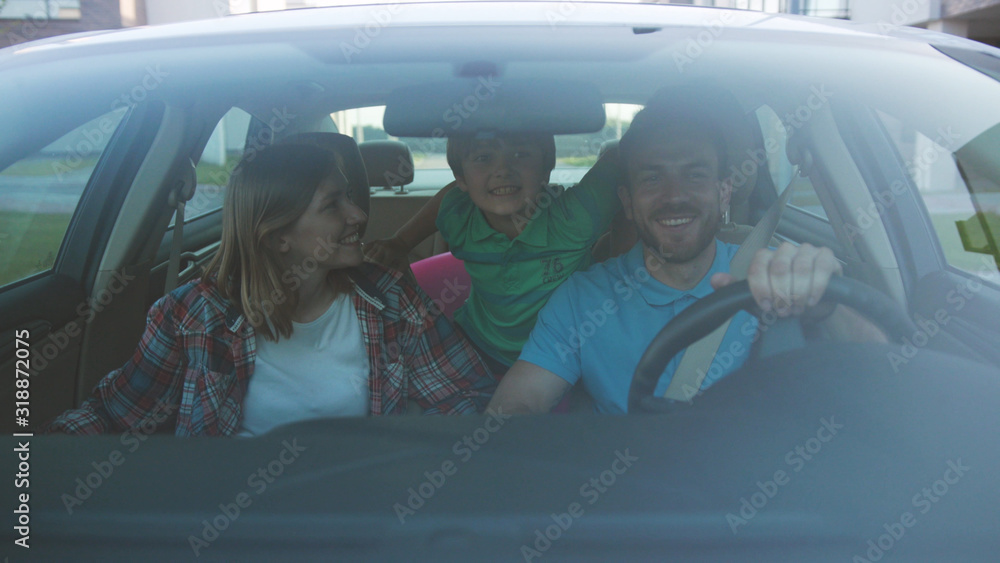 Wall mural NEW YORK - April 5, 2018: Happy excited young family having a fun roadtrip in the city center. Front view of parents and kids riding a car as part of their summer tour.