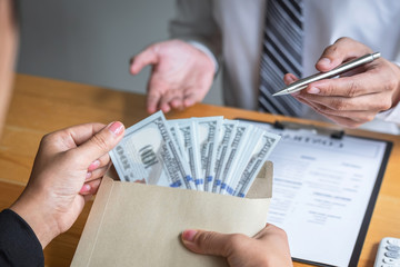Dishonest cheating in illegal money, Business woman giving bribe money the form of dollar bills to while give success the deal to contract agreement, Bribery and corruption concept
