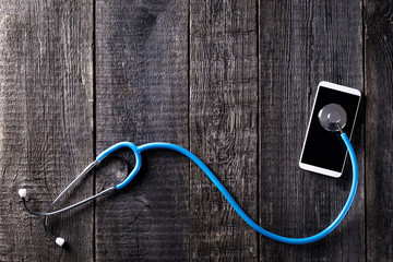 Smartphone and stethoscope on wooden rustic background