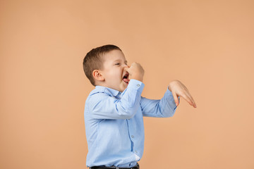 little child boy in blue shirt doing gesture smells bad on beige background. facial expression. kid...