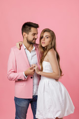 happy couple in love embracing on pink background. man in a jacket and a woman in a dress are happy together. st valentines day.