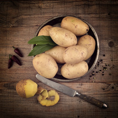 Still life. Potatoes, knife and bay leaf  on a vintage wooden dark background.