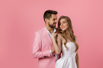 happy couple in love embracing on pink background. man in a jacket and a woman in a dress are happy...