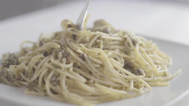 Close-up of an italian woman's hand rolls vegan spaghetti with broccoli and olive oil in the right way, in the studio with the steaming dish - 4k slog3 ungraded food footage