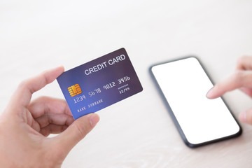 Hand holding credit card and touch smartphone defocus