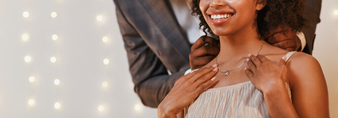 Cropped of man putting beautiful necklace on woman neck - obrazy, fototapety, plakaty