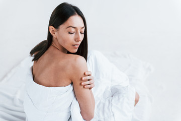 Young woman in underwear and with nice body shape sits in the studio against white background