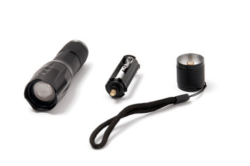 Small black pocket lamp on a gray wooden table on a white background. Turned off flashlight...