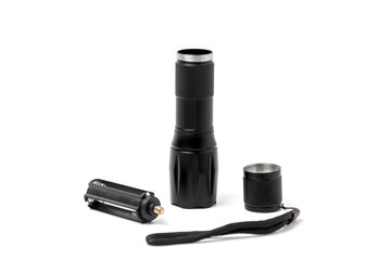 Small black pocket lamp on a gray wooden table on a white background. Turned off flashlight close-up on a light background. Disassembled flashlight.