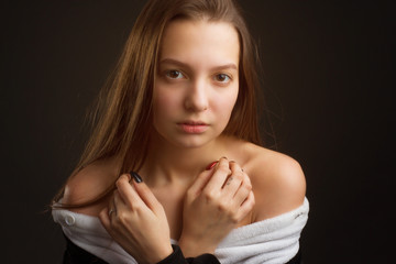 Fototapeta premium portrait of a brunette girl in the Studio on a plain black background in black and white pajamas with a hood
