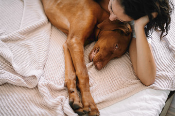 Girl with dog. Young woman laying with her dog in bed. 
