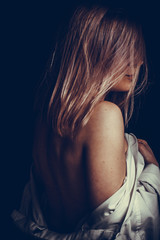 portrait of a blond girl wrapped in a white shirt Studio photo on a dark gray background.