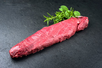 Rohes dry aged Hirschfillet Steak natur mit Kräuter angeboten als closeup auf einem Modern Design...