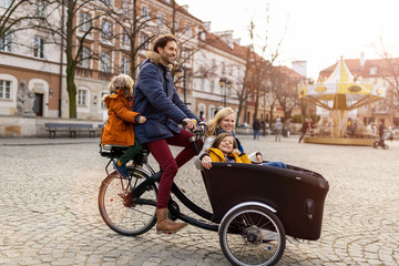 Young family enjoying spending time together, riding in a cargo bicycle