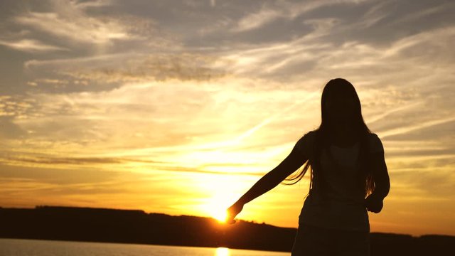 Free and cheerful woman. Happy girl with long hair is dancing at sunset on beach and laughing. Slow motion