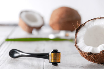 Coconut halved, essential oil in a glass bottle, cream and facial massager on a gray wooden table. Personal care. Spa treatments. Cosmetology. Natural and organic cosmetics.