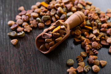 Healthy dry pet food in a wooden spoon on the black table