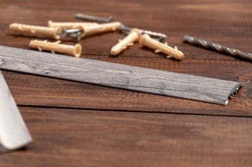 Tools on a gray wooden table. Screws, dowels, door sills for interior doors.