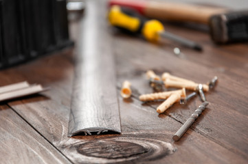 Tools on a gray wooden table. Miter box, screwdriver, screws, dowels, sills for interior doors.