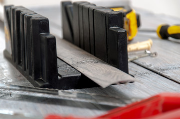 Tools on a gray wooden table. Hacksaw for metal, miter box, screwdriver, screws, dowels, sills for...