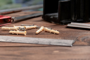 Tools on a gray wooden table. Hacksaw for metal, miter box, screwdriver, screws, dowels, sills for interior doors.