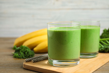 Tasty fresh kale smoothie on wooden table, closeup