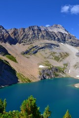 Beautiful blue Hamilton Lake high in the mountains. Rocky mountains, steep shore, pine trees. Blue sky, sunny day. Canada.