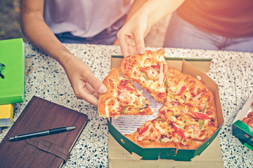 office people group taking and sharing pizza slices from box on table. Employees team workers eating together enjoy at work break, delivery service concept.