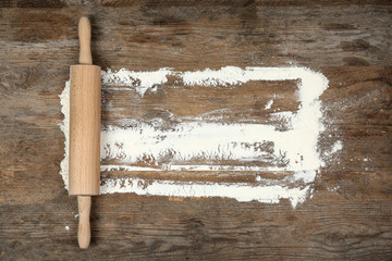 Flour and rolling pin on wooden table, flat lay