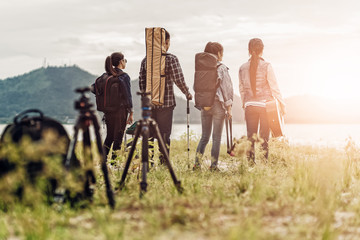 A group of friends traveling and camping near lake and mountain back.