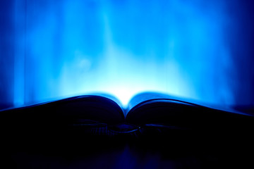 An open book with a glow in the background.