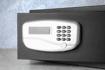 Black steel safe with electronic lock on grey marble table, closeup